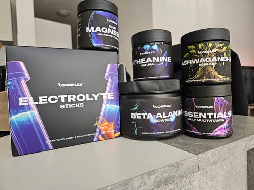 Reviewer's tub of Natural L-Theanine shown with other Complex brand supplements on a grey counter.