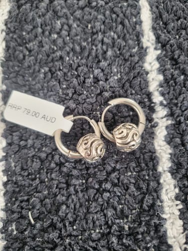 Customer's silver hoop earrings with ornate beads, received from the Surprise Box, shown with a price tag of RRP 79.00 AUD.