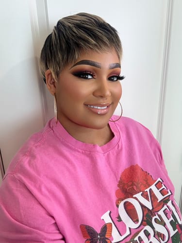 Reviewer smiling while wearing a short, edgy wig with blonde highlights and dark roots.