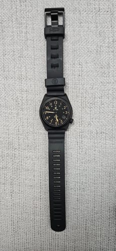 Customer's black Divecore diving watch strap attached to a black watch, laid out flat on a grey surface.