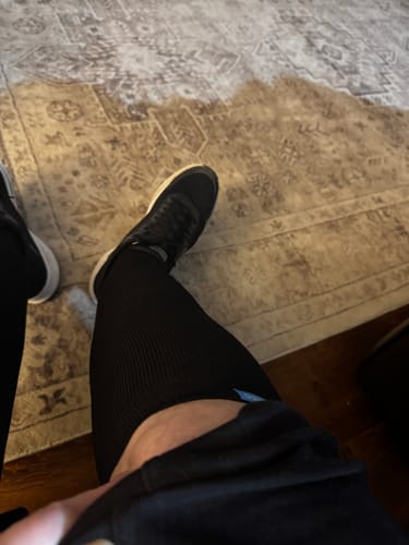 Customer's left leg shown wearing a black Performance Eucalyptus Compression Sock and a sneaker.