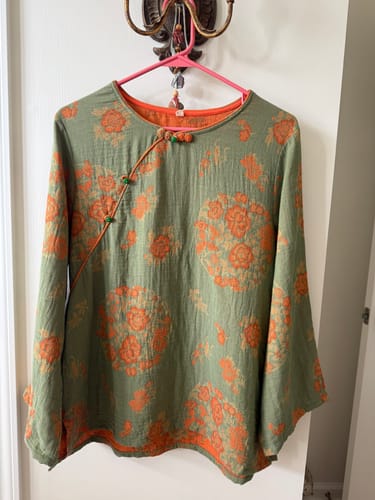 Customer's green floral long-sleeve shirt from the set hanging on a hanger.
