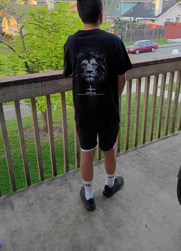 Reviewer showing the back of the black Joshua 1:9 Lion Oversized T-Shirt, displaying the bold lion graphic while standing outdoors.
