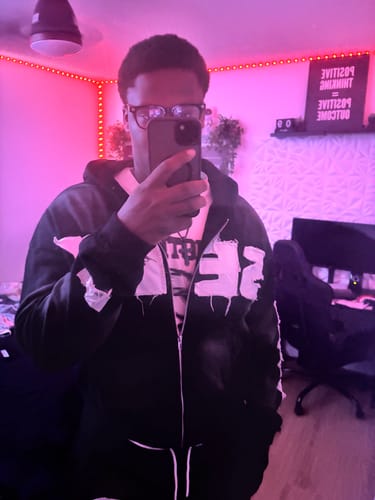 Reviewer taking a mirror selfie while wearing the black graphic SEEK VISIONZ SET in a dimly lit room.
