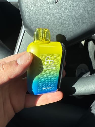 Reviewer's hand holding the yellow and blue Randm Tornado 20000 vape in the Blue Razz flavor.