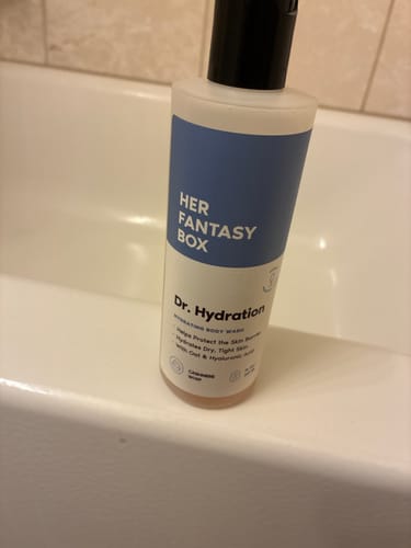 Customer's bottle of Dr. Hydration body wash with its blue label, shown resting on the edge of a bathtub.