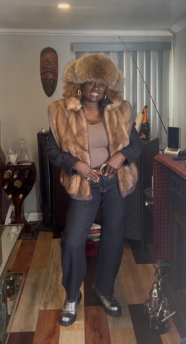 Reviewer posing indoors wearing the dark denim shirt open, layered under a brown fur vest.