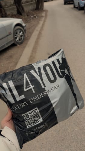 Клиент държи брандираната опаковка за памучни прашки ALL Black на открито.