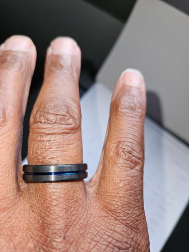 Close-up of a customer's hand wearing the Stratus ring, showing the brushed texture and central blue groove.