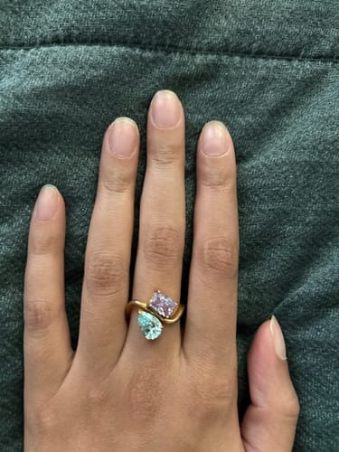 Customer wearing the Navae Birthstone Ring with a flowing gold band holding light blue and purple stones.