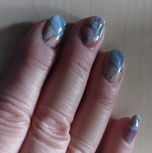 Nahaufnahme der Hand einer Kundin mit den 'Pieces Of This' Nagelfolien in einem zarten, pastellfarbenen Design.