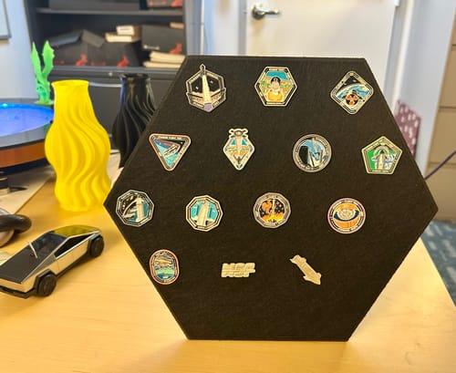 Customer's SpaceX Starship Flight Pin Collection arranged on the black hexagonal display mount standing on a desk.
