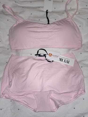 Reviewer's pink Cloud Lounge Bralette and matching bottoms laid out flat on a bed, with tags still attached.