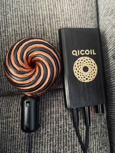 Reviewer's black Qi Coil Mini System, with the copper wire coil and power unit displayed on a textured couch.