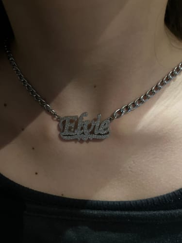 Eine Rezensentin trägt die silberfarbene, funkelnde Diamond Drip Namenskette am Hals.