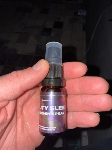 Close-up of a customer holding the bottle of Melatonin Sleep Spray in their hand.