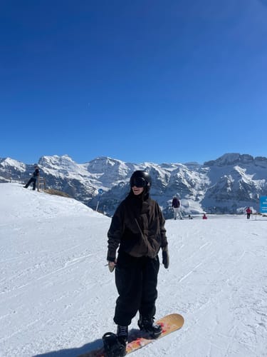 Reviewer snowboarding in the oversized dark Snow Jacket on a mountain.