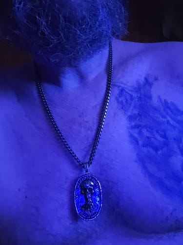 A reviewer wears the Memento Mori Vita Et Mors Necklace on their chest, with a tattoo visible on their shoulder.
