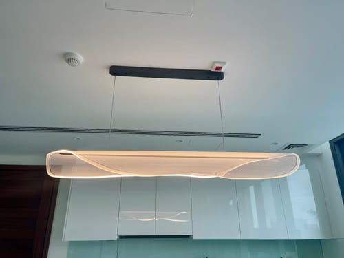 Customer's Lustrion Pendant Lamp illuminated and hanging over a kitchen island, showcasing its long, wavy design.