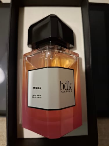Recensore mostra il flacone di Impadia eau de parfum, con vetro sfumato arancio e rosa, nella sua scatola.