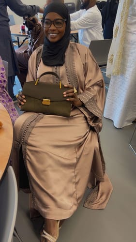 Customer wearing her beautiful, light-colored Digna dress while seated at an event.