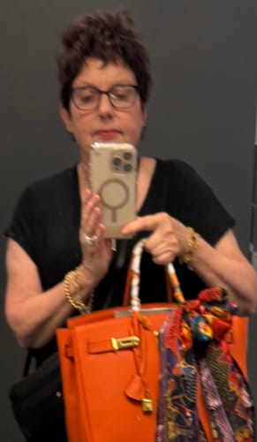 Reviewer taking a mirror selfie holding their bright orange LALUVA Warkin Bag with a scarf on the handle.