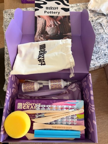 Reviewer's open This Month's Craft Subscription Box showing all the pottery supplies inside.