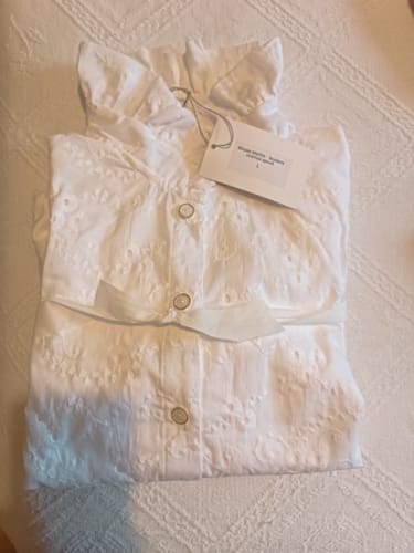 Avis d'un client montrant la Blouse Marthe blanche pliée, avec sa broderie ajourée et son étiquette.
