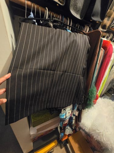 Customer holding their black Suiting Pinstripe Wide-Leg Pant in a closet.