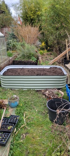 Customer's light green 17” Tall Modular garden bed, assembled and filled with soil in a backyard setting.