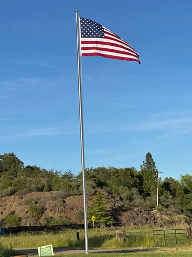 Customer's heavy duty American flag unfurled in the wind on a tall flagpole.
