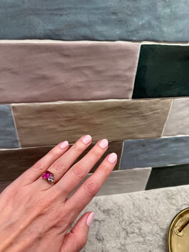A reviewer's hand wearing the Toi Et Moi Birthstone Ring with prominent pink and light purple stones.