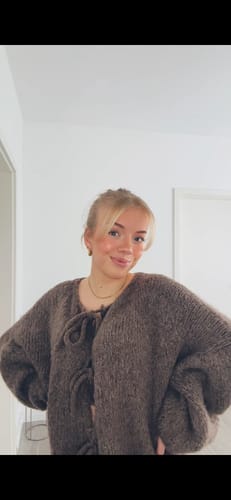 Kundin trägt den weichen Oversized Cardigan mit Schleifen in Braun.