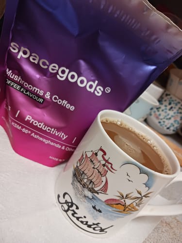 A customer's purple bag of rainbow dust sits next to a mug filled with the prepared coffee.