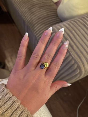 Customer showing their Navae Birthstone Ring with vibrant purple and green stones on their hand.