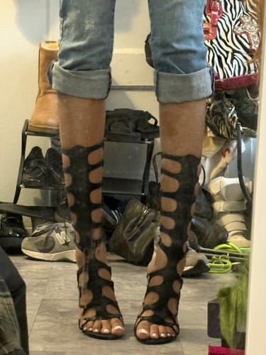 Reviewer standing in the tall, black Snake Heel, showing the full cutout design up the leg with cuffed jeans.
