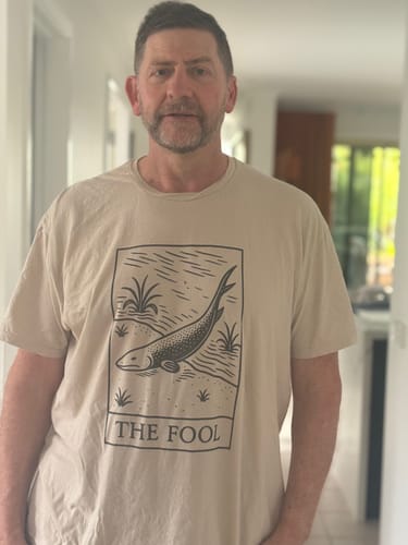 Reviewer wearing the beige Devonian Fool T-Shirt, showing the tarot card style graphic with a fish and 'THE FOOL' text.