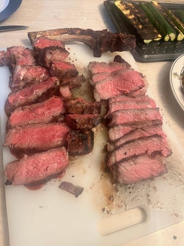 Reviewer's cooked Tomahawk Ribeye, sliced on a cutting board to reveal a juicy, medium-rare center.