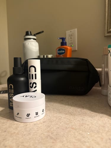 Reviewer's black Toiletry Bag on a bathroom counter surrounded by skincare products.