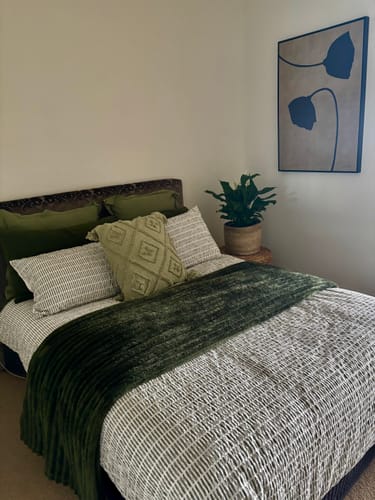 Customer's Dark Poppies framed art print hanging on a bedroom wall next to a plant.