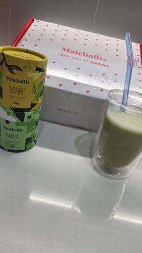 Un cliente muestra el Pack Experiencia Completa Premium con la caja, dos botes de té y un vaso de matcha preparado.