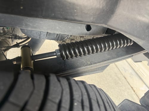 Customer's close-up view of the installed HD Kit, showing the black coil spring and hardware above the truck tire.