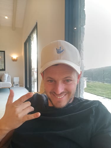 לקוח מחייך כשהוא חובש את כובע המצחיה בצבע קרם של LOUDER by Émily.