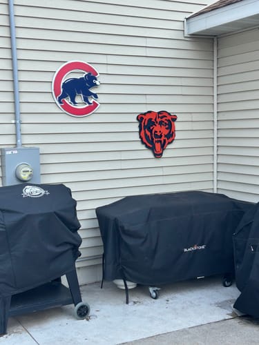 Reviewer's Chicago Bears 'Roaring Bear' wall art mounted on an outdoor patio wall above two covered grills.