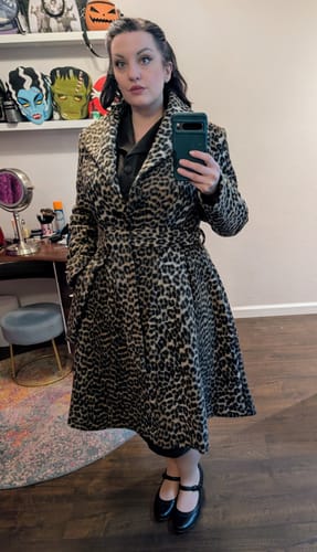 Reviewer shows off the flared, knee-length fit of the Starlet Swing Coat in leopard print.