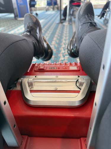 Reviewer resting their feet on a red Nobl carry-on suitcase in an airport.