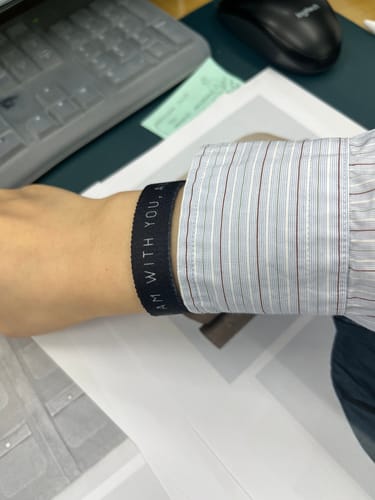 Reviewer wearing the black 'I Am With You, Always' Bible Verse Bracelet on their wrist at a desk.