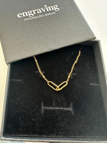 Customer's gold Infinity Link Necklace displayed in its open black jewelry box.