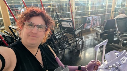 Reviewer sitting in an airport terminal with their light purple Weekender Bag and matching luggage.