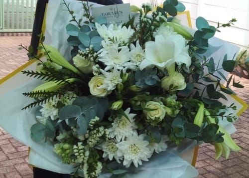 Customer holding their large, fresh Classic White Bouquet with white flowers and greenery.